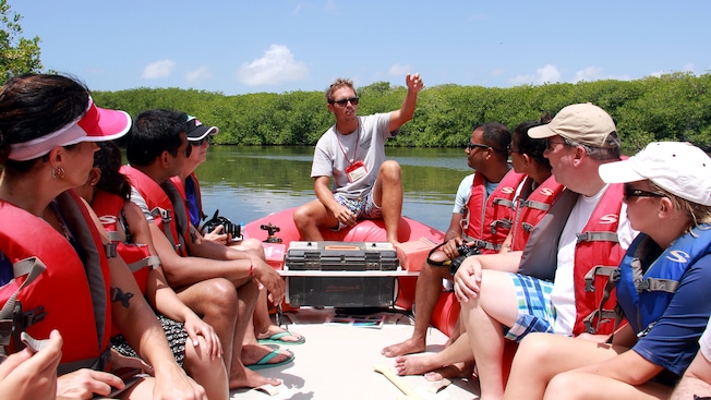 Un guía habla a personas en un bote inflable cerca de un bosque de manglares Un guía habla a personas en un bote inflable cerca de un bosque de manglares