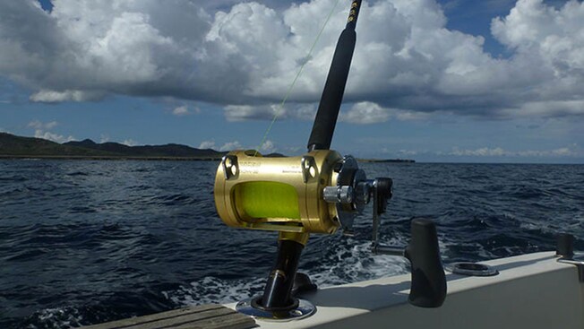 Una caña de pescar con un sedal conectado a un barco cerca de una isla