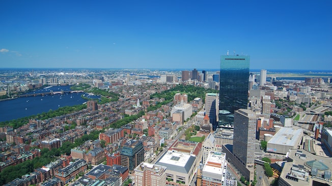 An expansive city view encompassing buildings, streets, trees, bodies of water, boats and sky An expansive city view encompassing buildings, streets, trees, bodies of water, boats and sky