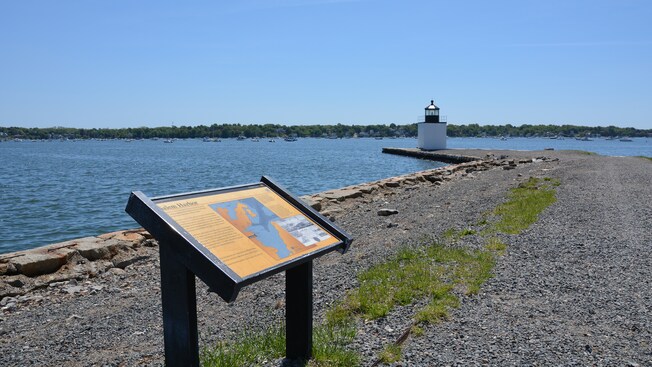 A plaque with information about Salem Harbor and a background featuring a lighthouse and an ocean