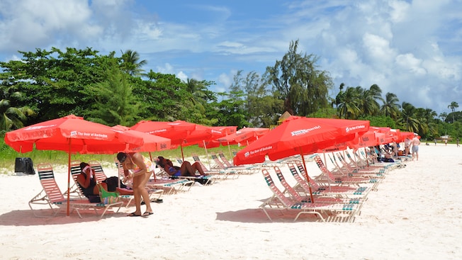 Guests relax on some of the available chaise lounges with umbrellas, shading them from the sun
