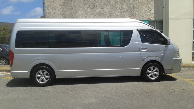 A touring van with a high passenger cab and tinted windows is parked in a lot