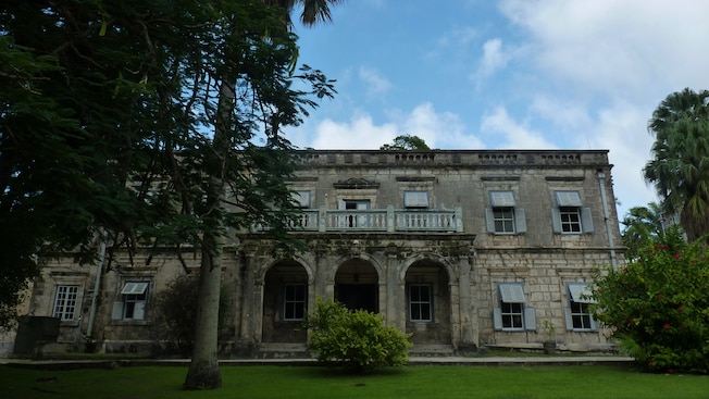 A large, 2 story stone building with an open balcony above the main entrance