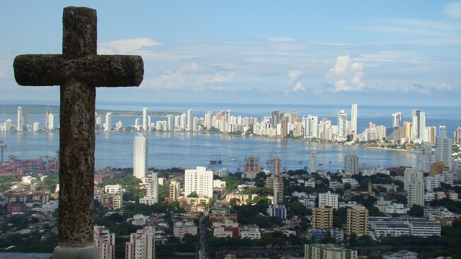 A Christian cross overlooks a sprawling city by a bay