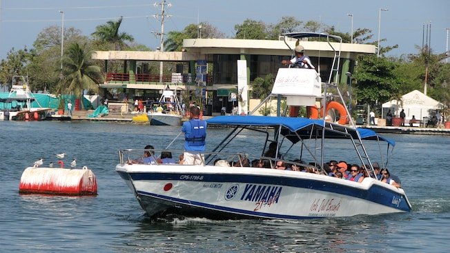 A passenger boat cruises around the bay of Cartagena, with the docks in the background A passenger boat cruises around the bay of Cartagena, with the docks in the background
