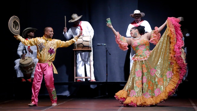 2 performers dance on stage while a band plays behind them 2 performers dance on stage while a band plays behind them