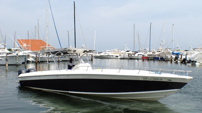A man steers a boat through the marina in Cartagena Bay, with other boats lined up in the background A man steers a boat through the marina in Cartagena Bay, with other boats lined up in the background