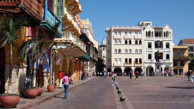 People walk by 17th century colonial buildings in a colonial plaza in old town Cartagena People walk by 17th century colonial buildings in a colonial plaza in old town Cartagena
