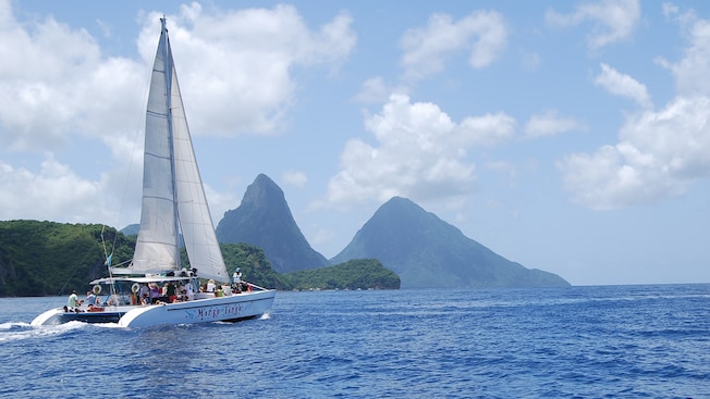 A catamaran carries passengers across the ocean toward mountains