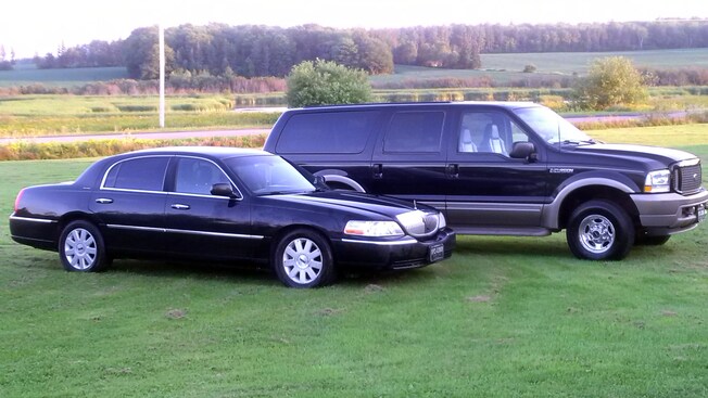 A sedan and an SUV featuring tinted windows parked on the grass