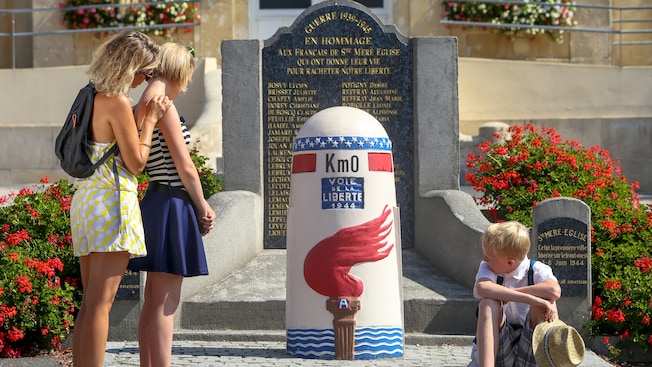2 women and a boy stare at a painted milestone by a plaque 2 women and a boy stare at a painted milestone by a plaque