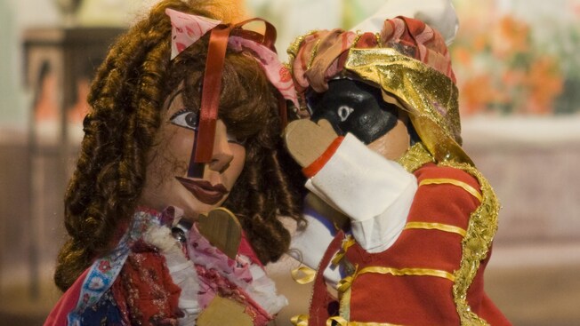 A man puppet tells a secret to a woman puppet
