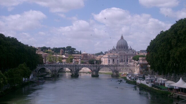 An old bridge in front of Saint Peters Basilica, a building in Rome with a dome shaped roof