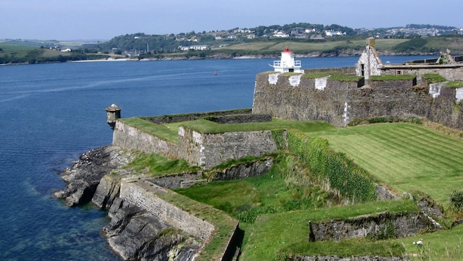A centuries old stone fortification with grassy banks situated along a rocky shoreline A centuries old stone fortification with grassy banks situated along a rocky shoreline