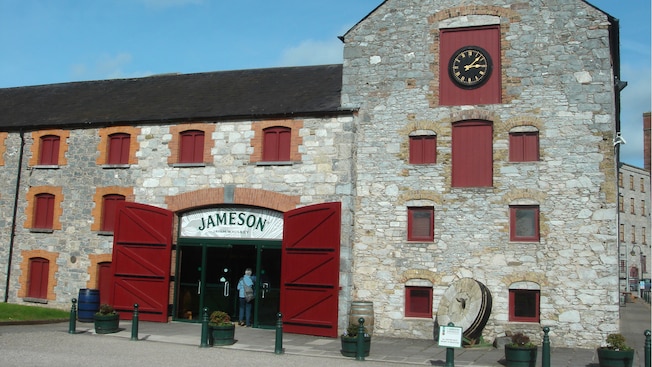 Uma construção de pedra com um relógio e uma placa que diz Jameson Uma construção de pedra com um relógio e uma placa que diz Jameson