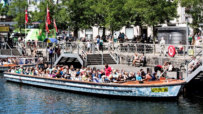 Passengers aboard a tour boat docked alongside the canal