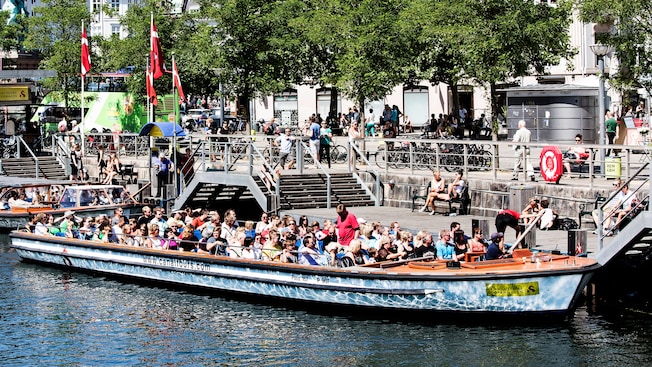 Pasajeros a bordo de una embarcación turística atracada junto al canal Pasajeros a bordo de una embarcación turística atracada junto al canal