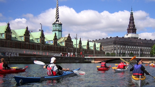 Kayakers paddle on a canal next to old buildings in Copenhagen, Denmark Kayakers paddle on a canal next to old buildings in Copenhagen, Denmark