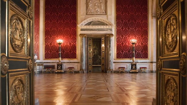Ornate doors open to a stately room with high ceilings, marble columns and velvet wall paper