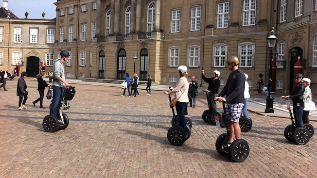 A tour group outfitted in helmets and standing on Segway scooters at Amalienborg Palace Square