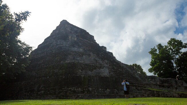 A young man taking a picture of a Mayan pyramid