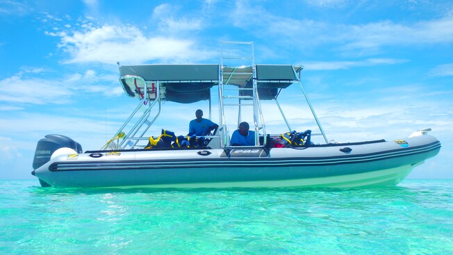 2 men sit amid snorkel vests in a rigid hull inflatable boat on the water