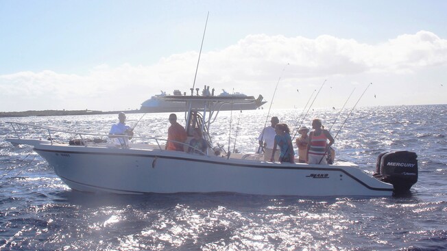 Un grupo de pescadores en un bote de pesca motorizado anclado cerca de un crucero de Disney