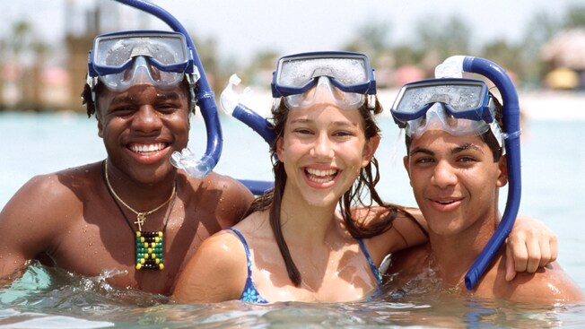 3 teenagers pose wearing their snorkel gear in the water