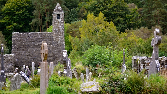 An old brick tower looms in the background of a cemetery with weathered headstones An old brick tower looms in the background of a cemetery with weathered headstones