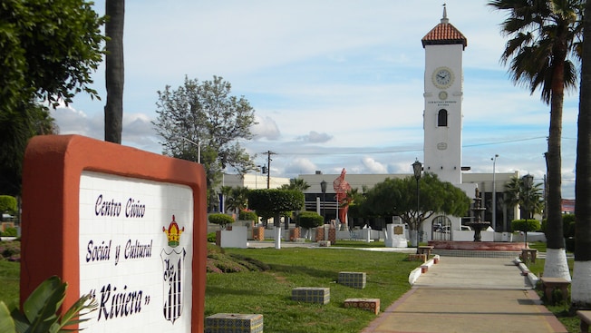 A fountain stands in front of a Spanish Colonial style building with a clock tower A fountain stands in front of a Spanish Colonial style building with a clock tower