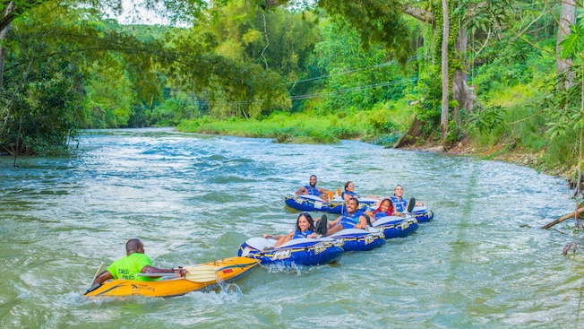 A group of people float in rafts down a river surrounded by jungle A group of people float in rafts down a river surrounded by jungle