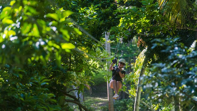 A woman hangs from a zip line in a jungle