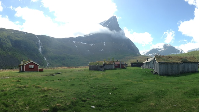 A plain with wood paneled buildings and a single large mountain peak in the distance A plain with wood paneled buildings and a single large mountain peak in the distance