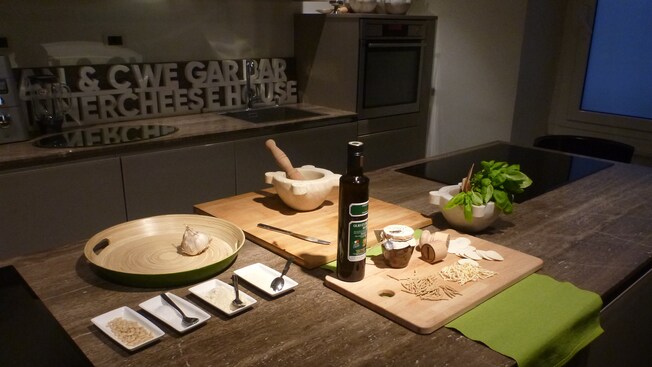 Una mesa preparada con condimentos, utensilios, una tabla para cortar, ajo y un mortero con maja