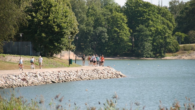 People biking, walking and walking with Nordic walker poles, on a path near the water in Helsinki People biking, walking and walking with Nordic walker poles, on a path near the water in Helsinki