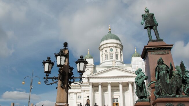 Statues of people near an ornate street light in front of a building