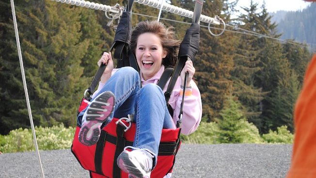 A woman smiles as she comes in for a zip line landing on a pebble beach