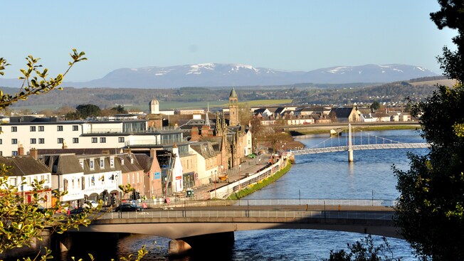 Bridges and a village with an enormous grassy field and mountains in the distance