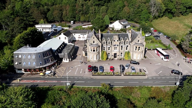 Uma moderno hotel ao lado de uma construção de estilo medieval identificado por uma placa como Loch Ness Centre