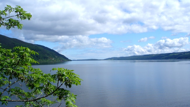 A vast body of water known as Loch Ness beneath partly cloudy skies