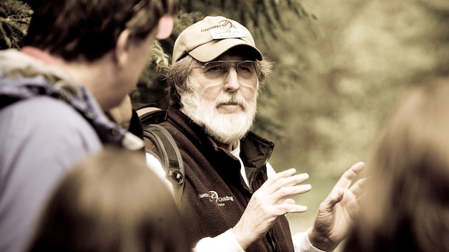 A man talks to a group of people in a forest A man talks to a group of people in a forest