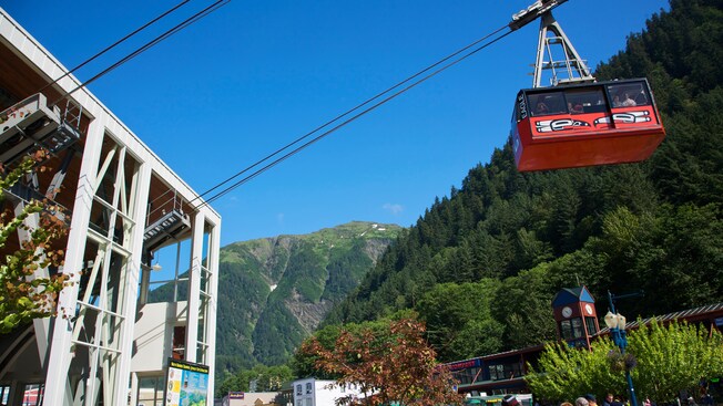 An aerial tram ascends from a station at the bottom of the mountain