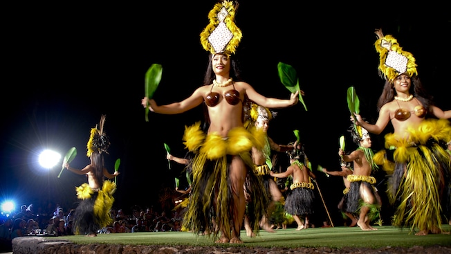Polynesian dancers shimmy, all holding a ti leaf in each hand and wearing traditional garb Polynesian dancers shimmy, all holding a ti leaf in each hand and wearing traditional garb