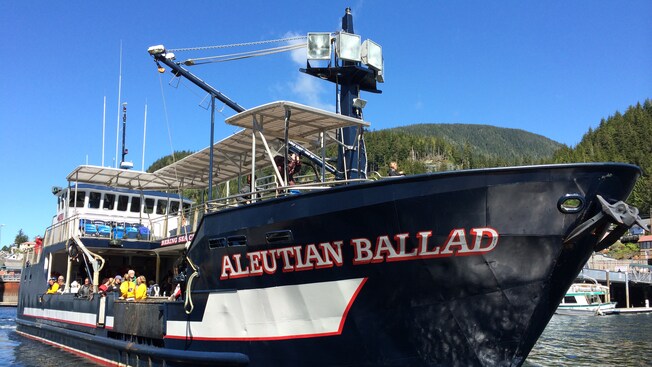 A sign on the side of a large fishing boat identifies it as the Aleutian Ballad