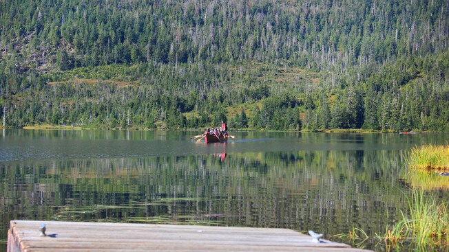 A small group paddling through a mountain lake in an oversized canoe