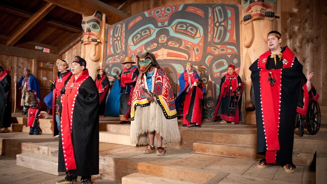 Performers in traditional Tlingit dress put on a show in a native lodge setting