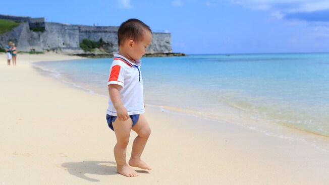 A baby walks on a beach