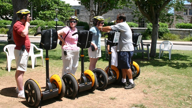 A tour guide helps a female Guest secure her helmet among 3 other Segway tour participants