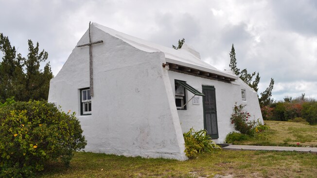 Uma capela com uma cruz de madeira perto de árvores e arbustos