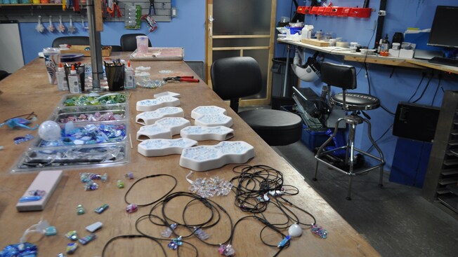 Una mesa cubierta de trozos de vidrio, cordel, moldes y pegamento en un taller
